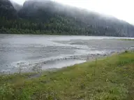 Small natural hot spring pool on the grassy bank of the South Nahanni River at Kraus Hotsprings