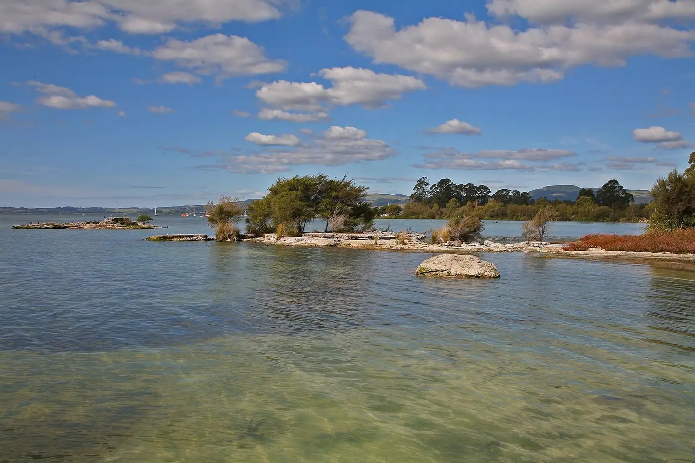 Clear shallows and small rocky islets of Lake Rotorua along the lakefront near Wai Ariki