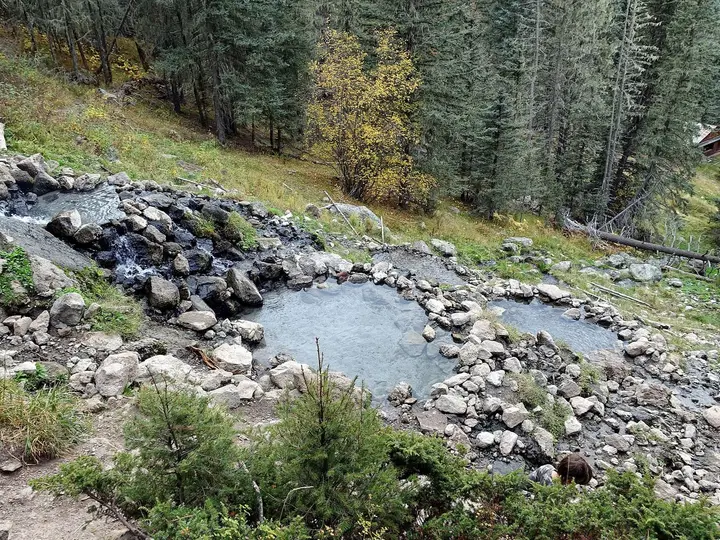 Rock lined pools of San Antonio Hot Springs stepping down a forested hillside with autumn color