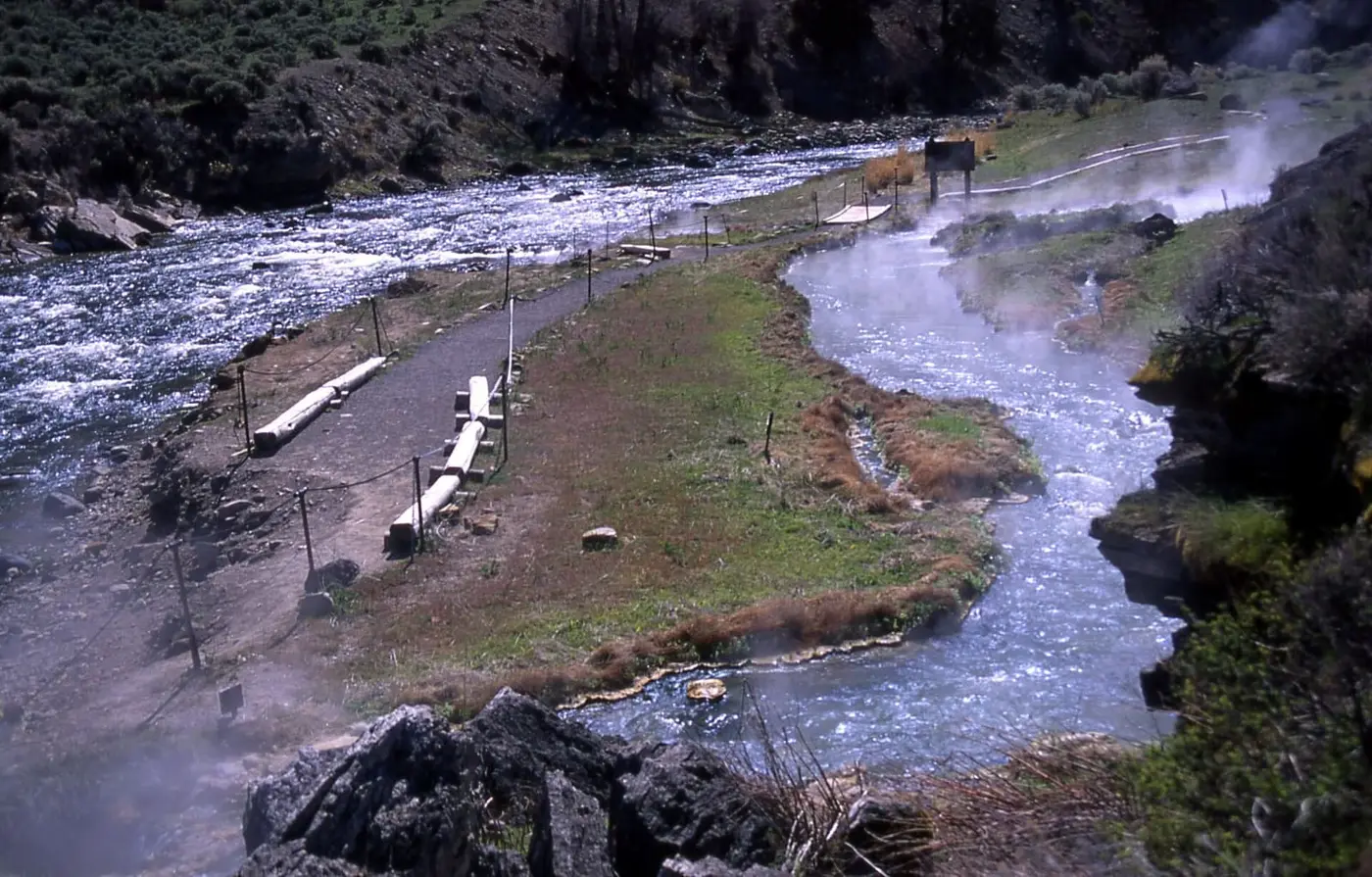 Steaming hot stream of Boiling River running beside the Gardner River along a fenced gravel path