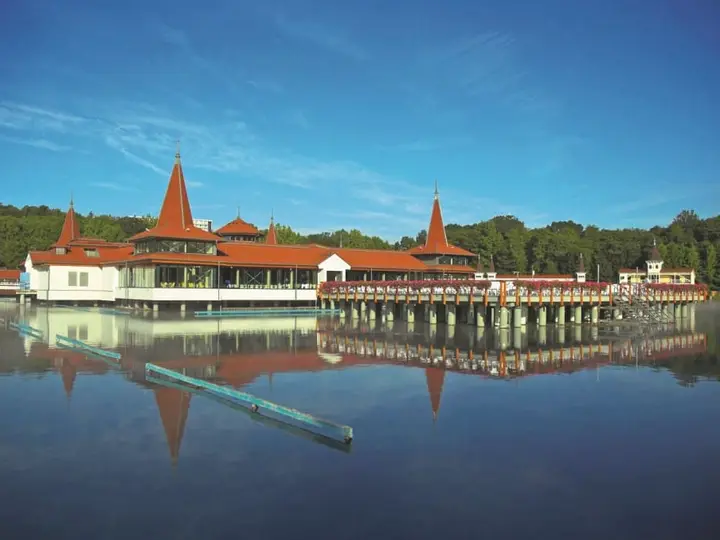 Lake Hévíz bathhouse with red turreted roofs reflected in the calm thermal lake
