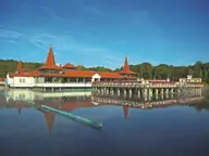 Lake Hévíz bathhouse with red turreted roofs reflected in the calm thermal lake