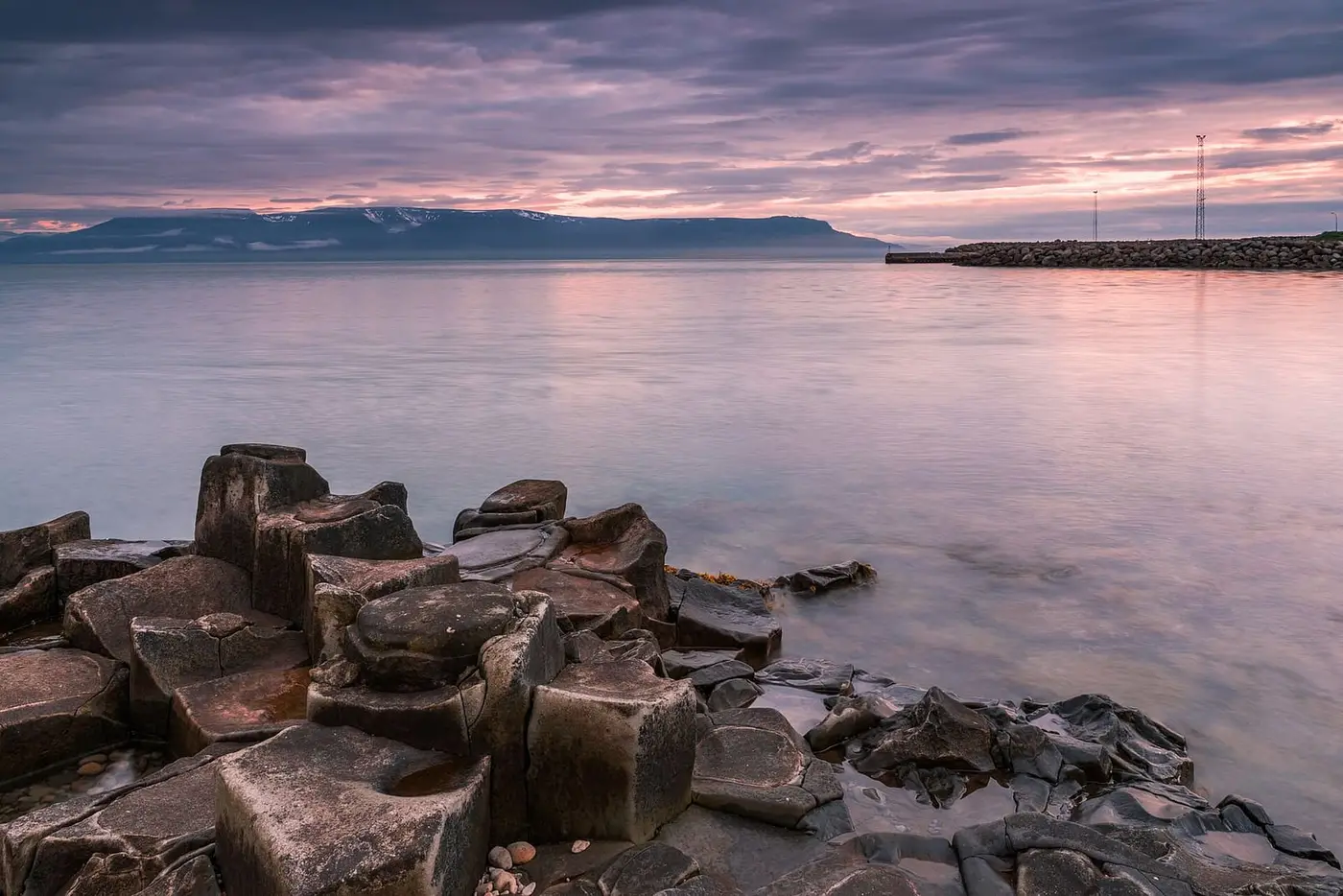 Basalt columns on the shore at Hofsós looking across Skagafjörður under a pink evening sky