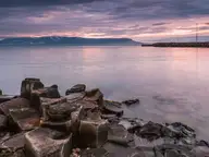 Basalt columns on the shore at Hofsós looking across Skagafjörður under a pink evening sky